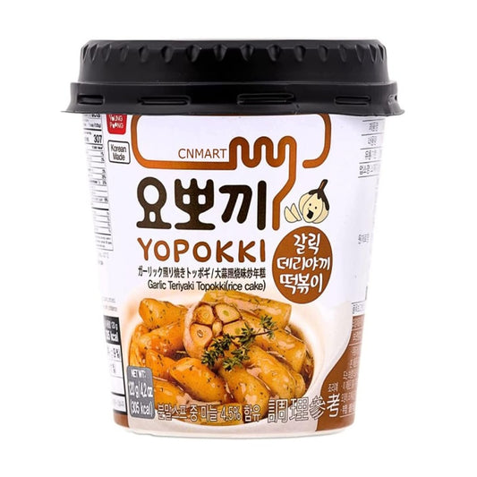 Yopokki Garlic Teriyaki Topokki 120g instant cup with black lid, showing Korean and English product name and an image of garlic-seasoned rice cakes on the front label.